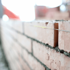 A plumb line over a course of bricks being set.