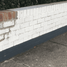 Restoration of a white brick wall after repairs and prior to repainting.